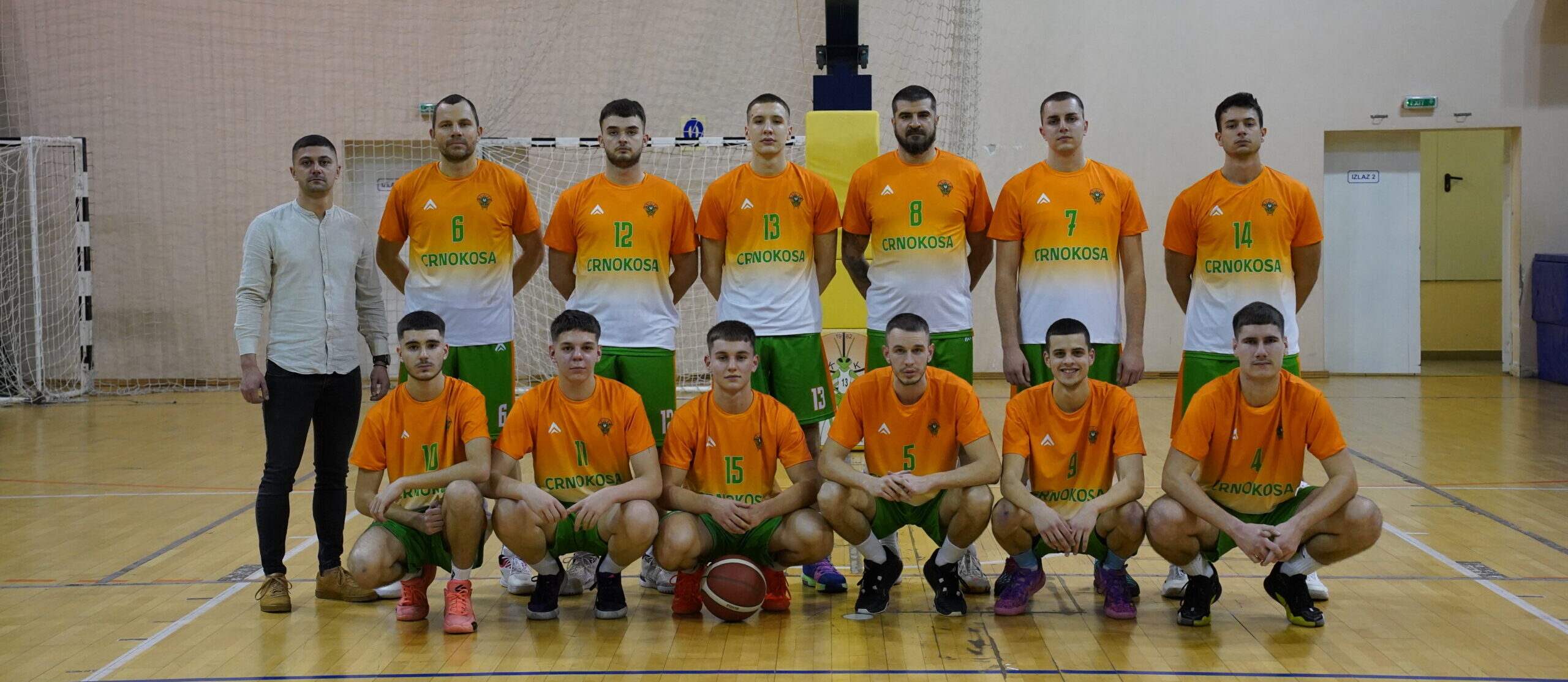 Tim košarkaša u dvorani, obučeni u narandžaste i zelene dresove.