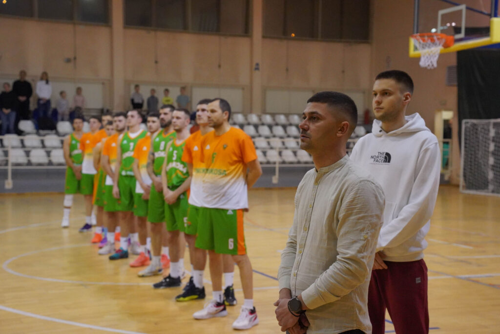 Košarkaški tim postrojen u sportskoj sali, zelene uniforme